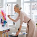 Mature woman painting with watercolors in a bright, modern studio