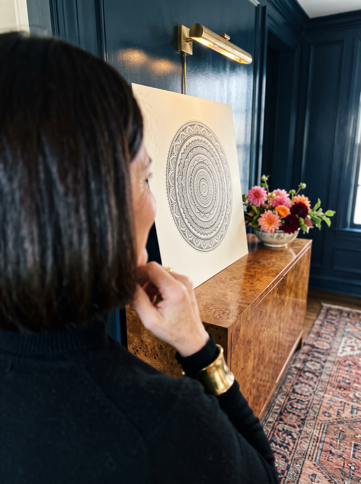Woman looking at a finished mandala drawing propped on a cabinet at home