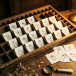 Birth month flower drawing: a shallow wooden specimen drawer pulled open, each compartment holding one small ink flower study