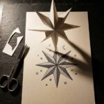 Celestial drawing: a cut-paper 8-point star standing on a sheet where the same star is drawn in flat tones