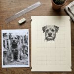 Grid method drawing in progress: a terrier photograph ruled with a grid beside a half-transferred pencil sketch