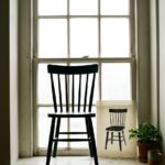 Negative space drawing cover: a kitchen chair silhouetted against a bright window beside a sheet where only the gaps between its rails are inked solid black
