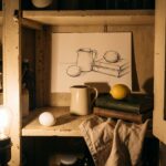 Still life drawing ideas cover: an open kitchen cupboard set up for drawing, an egg, a jug and a lemon at three heights beside the same group drawn in ink
