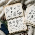 A thick sketchbook filled with winter drawing ideas in pen, open on wool with loose finished pages beside it
